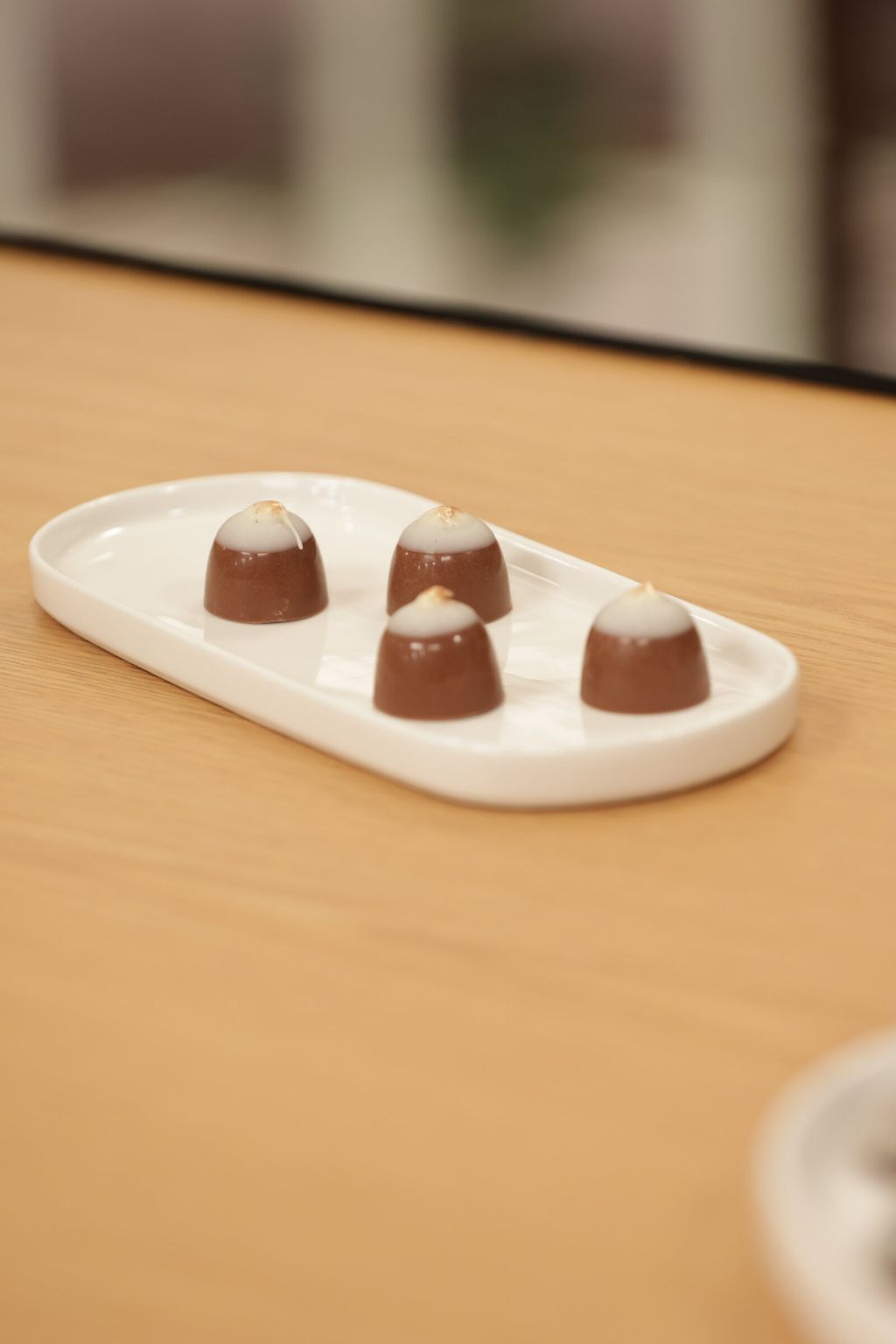Four chestnut-shaped «Winter Ember» bonbons on a white plate